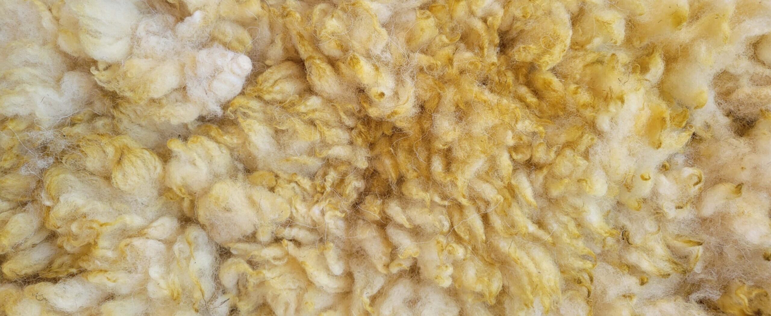 Close-up view of yellow fluffy insulation fibers with tangled, fuzzy texture
